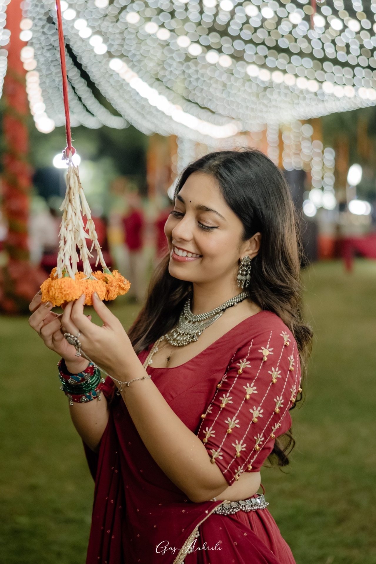 Woman in red holding a marigold and mogra bell