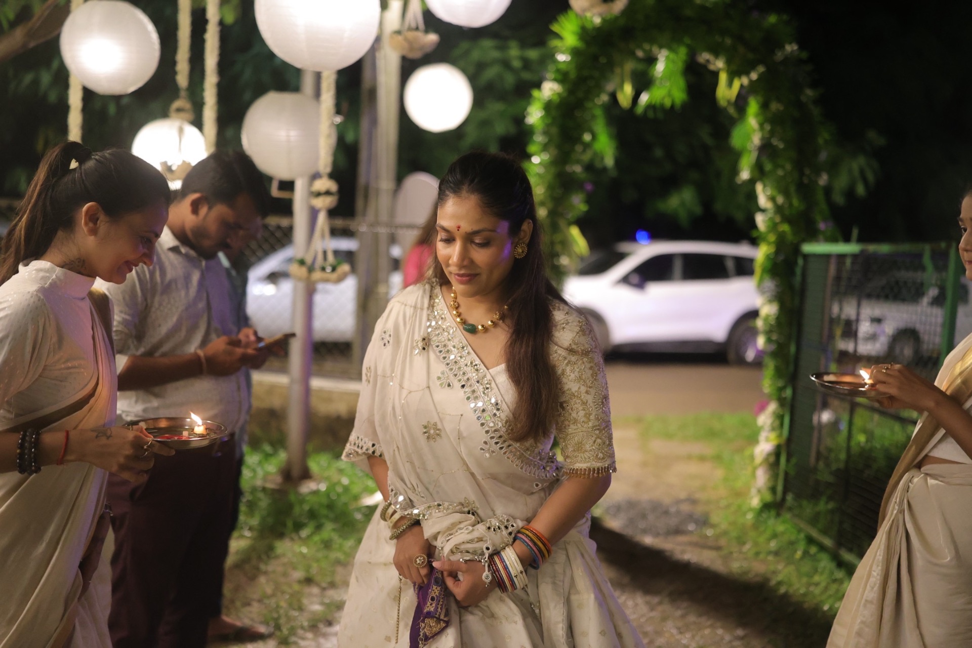 Guest in white saree holding a diya