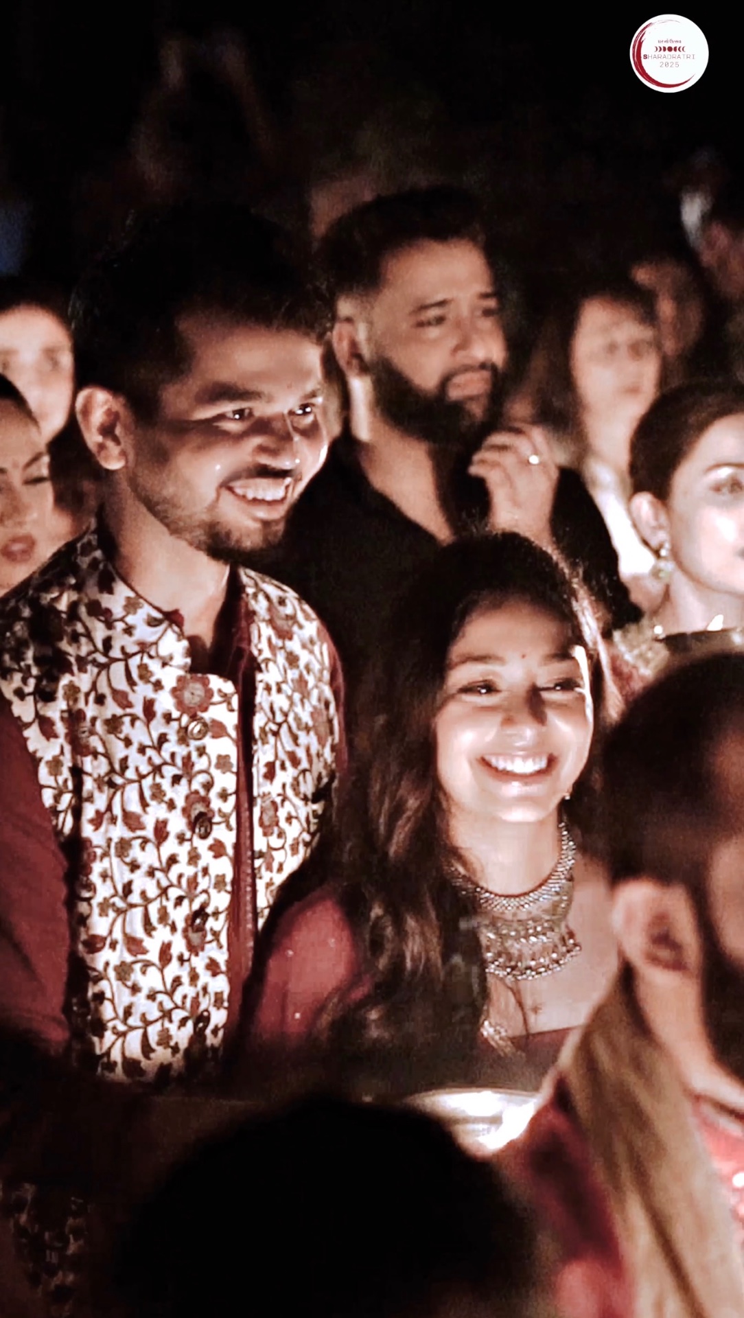 Couple smiling in the crowd, lit by aarti glow