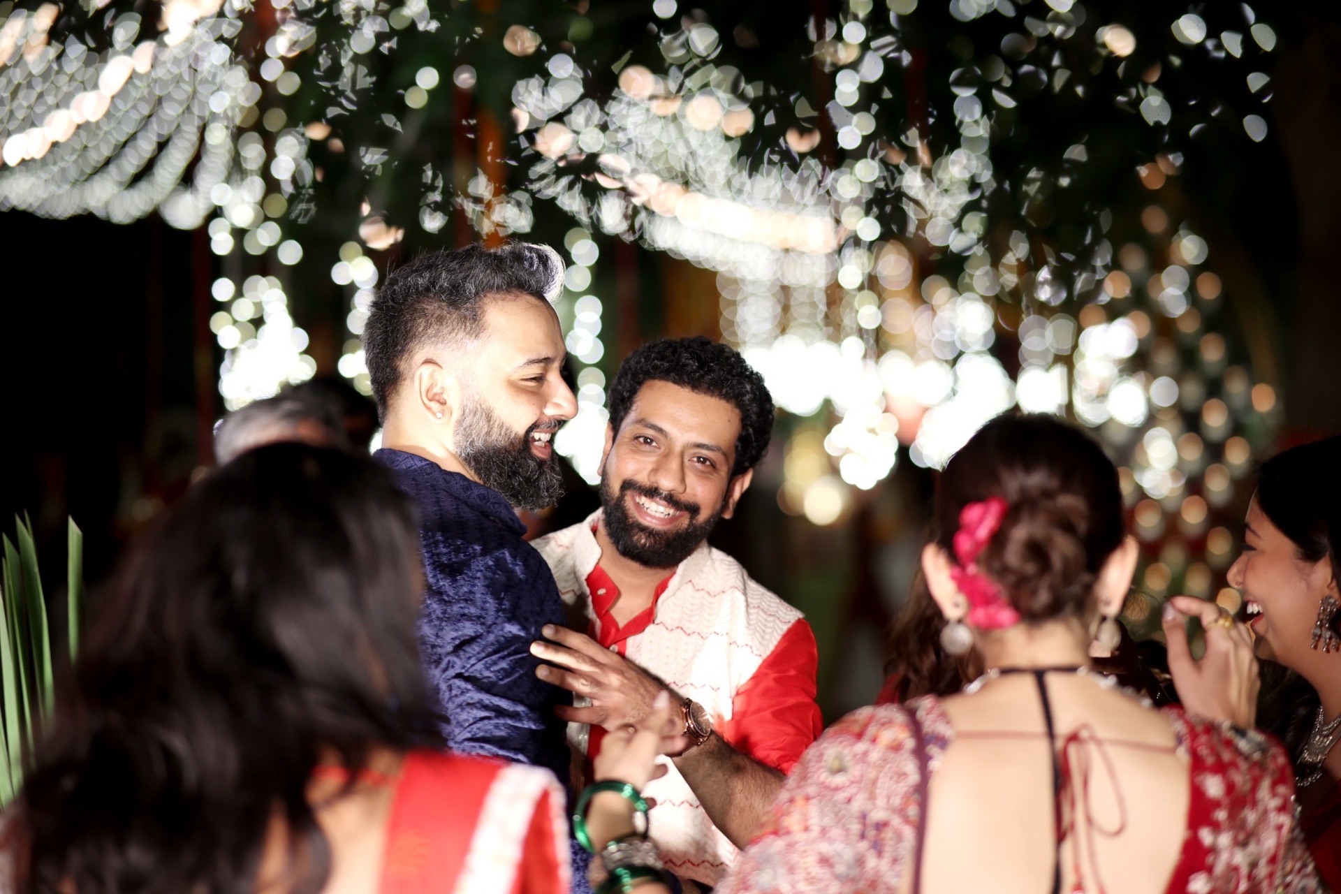 Friends laughing under confetti and fairy lights